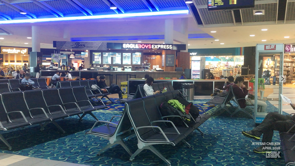 Cairns Airport's international departure lounge, with an Eagle Boys pizza kiosk and newsagent visible.