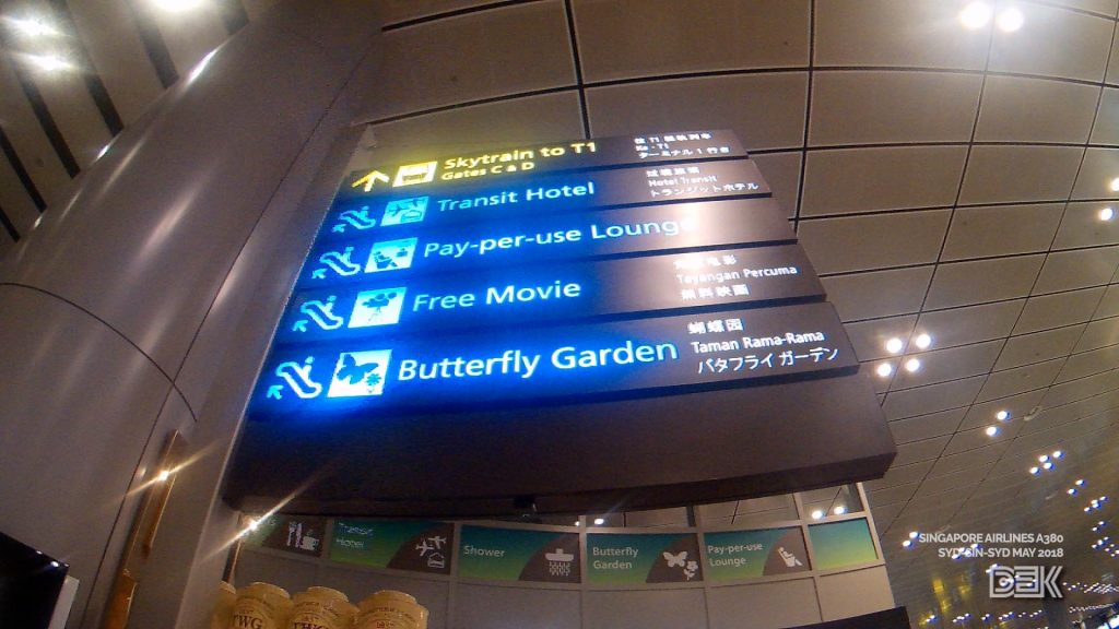 Signpost at Changi Airport, showing directions to Skytrain connection to Terminal 1, the Transit Hotel, Pay-per-use Lounge, Free Movie Theatre, and Butterfly Garden.