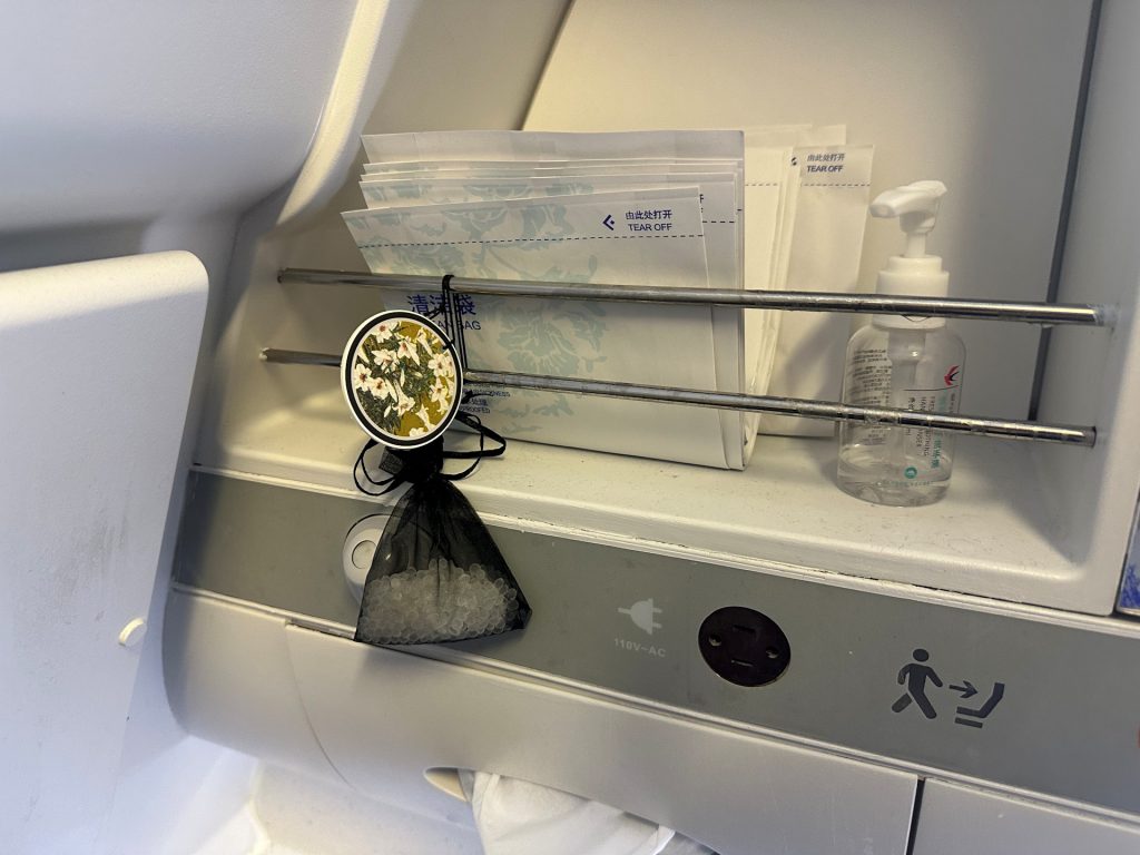 An air freshener hangs from the shelf in the aircraft lavatory.